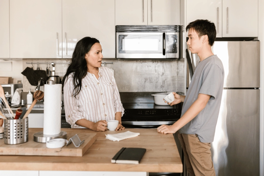 boy and girl roommate communicating in the kitchen with cups of tea